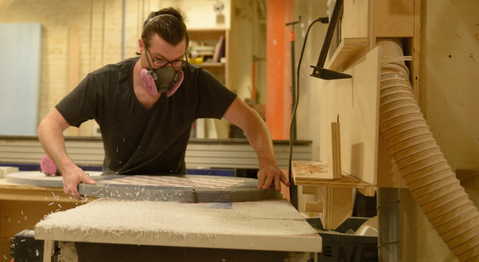 Ryan Hyde finishes a table edge on the router at NextFab